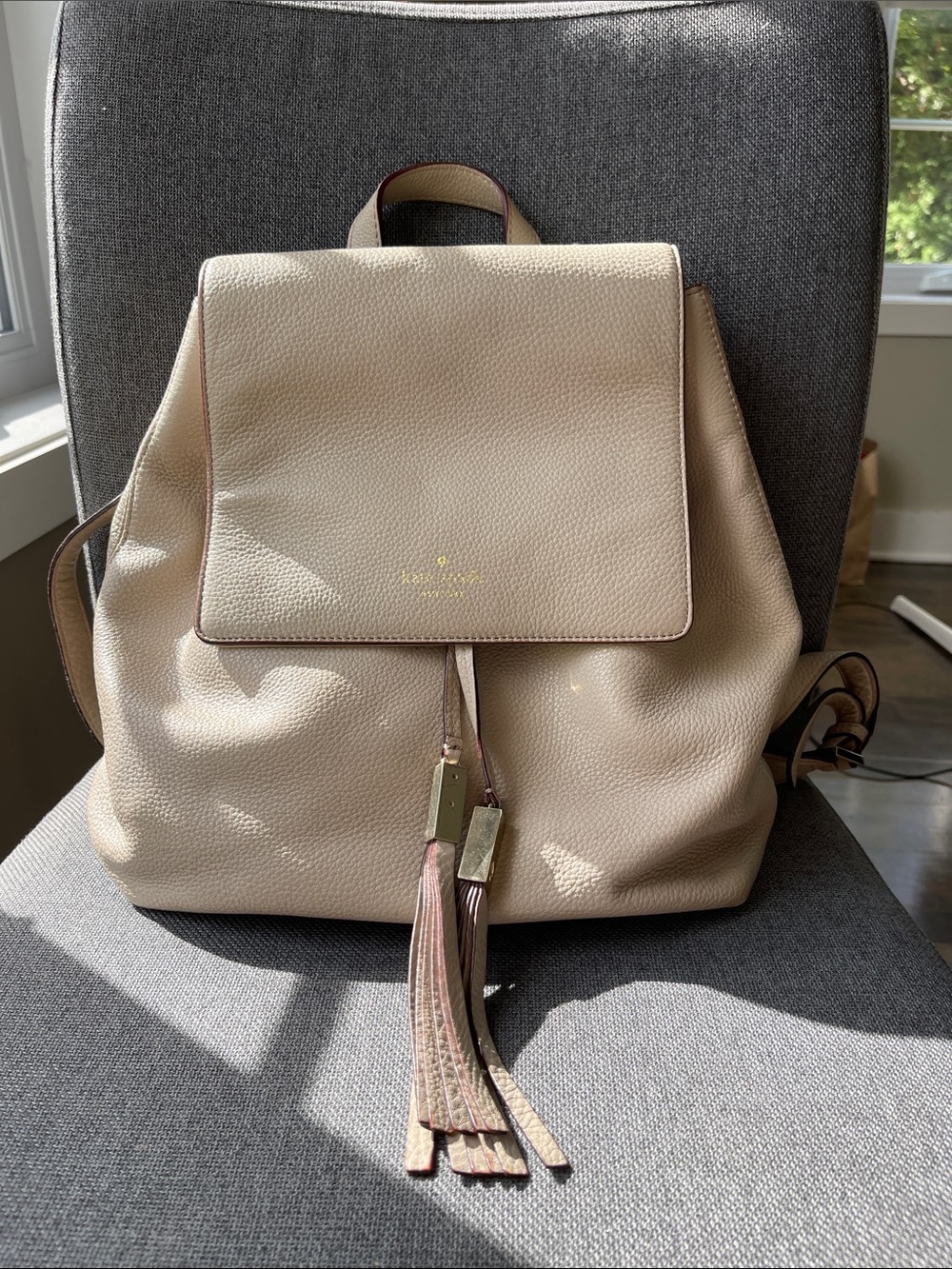 Kate Spade pebble leather flap backpack in light taupe and tassel